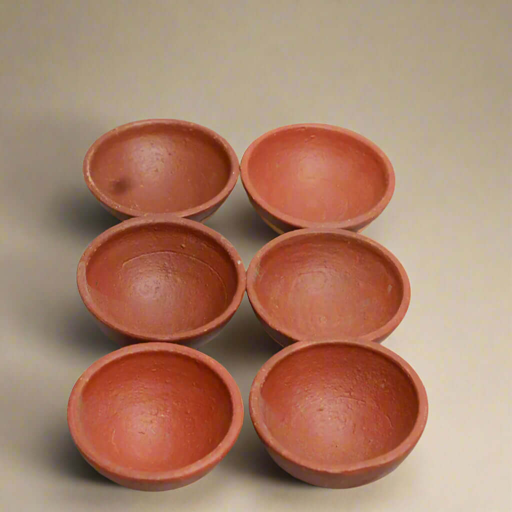 Six terracotta bowls arranged in a circle on a beige background